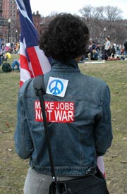 Woman's back, wearing peace sign and "Make Jobs, Not War" sticker.